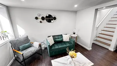 a living room with a green couch and a staircase at Modern Apartment Near Tweed -Yale -New Haven in New Haven