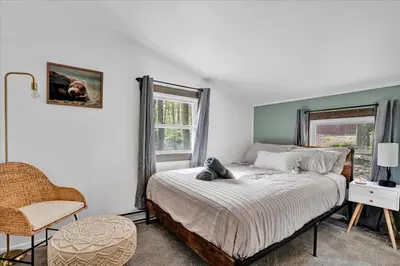 a bedroom with a bed and a chair and a window at Tranquil Trails Cottage Fire Pit Cozy 3BDR in Gouldsboro