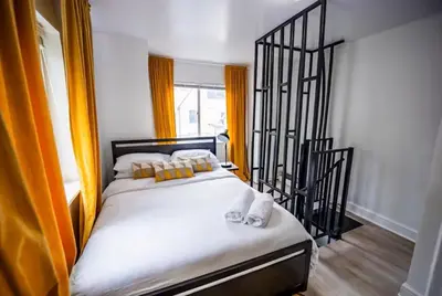 a bed in a room with orange curtains at Bright 1-Bedroom Loft in Converted Garage with Private Entrance in New Rochelle