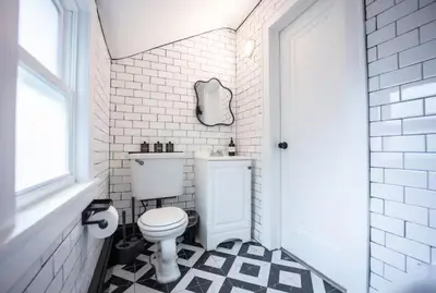 a bathroom with a toilet and a black and white tile floor at Bright 1-Bedroom Loft in Converted Garage with Private Entrance in New Rochelle