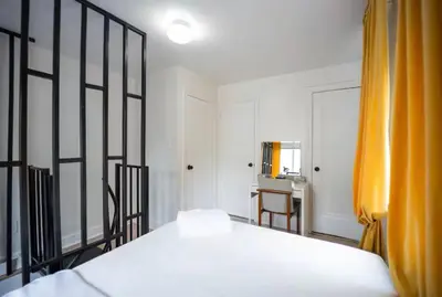 a bedroom with a bed with an orange curtain at Bright 1-Bedroom Loft in Converted Garage with Private Entrance in New Rochelle