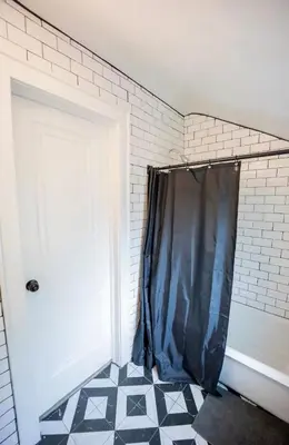 a bathroom with a black shower curtain next to a door at Bright 1-Bedroom Loft in Converted Garage with Private Entrance in New Rochelle