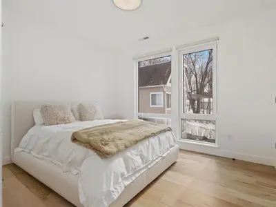 a white bedroom with a bed and a window at Modern living on the Quinnipiac River in New Haven