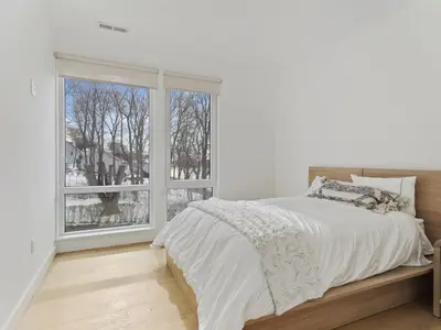 a white bedroom with a bed and a large window at Modern living on the Quinnipiac River in New Haven