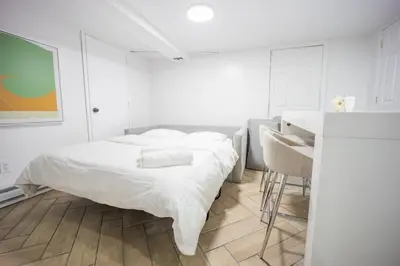 a white bedroom with a bed and a table at Retro 2 bedroom basement APT with free parking in New Rochelle