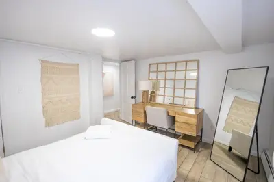 a white bedroom with a bed and a desk at Retro 2 bedroom basement APT with free parking in New Rochelle