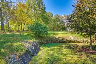a creek in a field with trees and grass at New Milford Home 29 Mi to Lime Rock Park! in New Milford