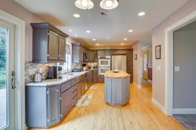 a large kitchen with wooden floors and gray cabinets at New Milford Home 29 Mi to Lime Rock Park! in New Milford