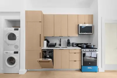 a kitchen with brown cabinets and a washer and dryer at 19-4G 2BR 2Baths Luxury Apt East Village in New York