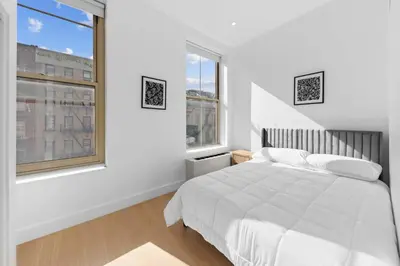 a white bedroom with a bed and two windows at 19-5D 2BR 2Baths Luxury Apt East Village in New York