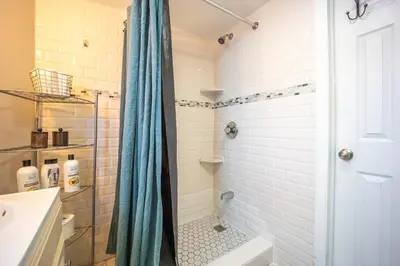 a shower with a blue shower curtain in a bathroom at Bright 3bed basement with backyard & free parking in Yonkers