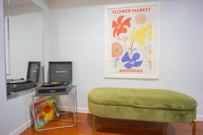 a room with a green ottoman and a sign on the wall at Bright 3bed basement with backyard & free parking in Yonkers