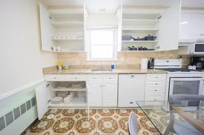 a white kitchen with white cabinets and a window at 3bedroom APT with balcony & free street parking in Yonkers