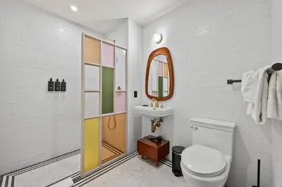 a bathroom with a toilet and a sink and a mirror at Freeman 602 by Rove Travel - Condo with Shared Amenities in New York