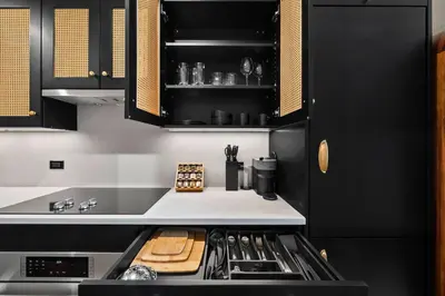 a kitchen with black cabinets and a stove top oven at Freeman 603 by Rove Travel - Studio with Shared Amenities in New York