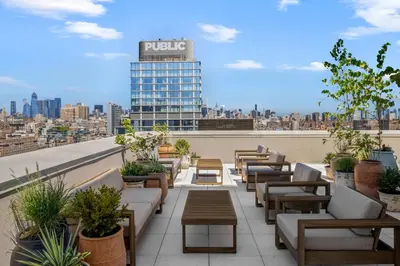 a rooftop patio with couches and tables and a building at Freeman 201 by Rove Travel - 2BR Condo with Shared Amenities in New York