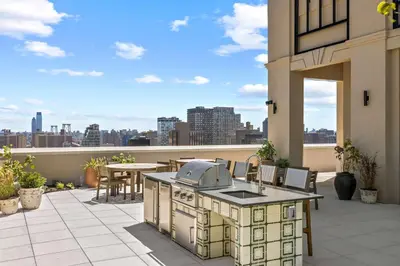 an outdoor kitchen on a patio with a view of the city at Freeman 201 by Rove Travel - 2BR Condo with Shared Amenities in New York