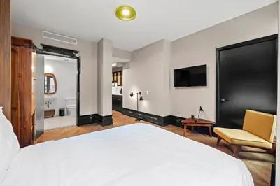 a bedroom with a bed and a tv and a chair at Freeman 201 by Rove Travel - 2BR Condo with Shared Amenities in New York