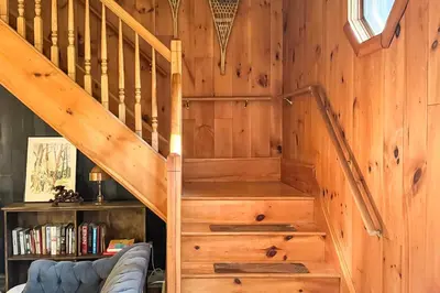 a wooden staircase in a room with a book shelf at Secluded Family Getaway with On-Site Creek in Hawley in Hawley