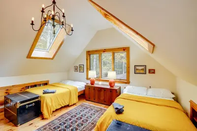 two beds in a attic room with a chandelier at Secluded Family Getaway with On-Site Creek in Hawley in Hawley
