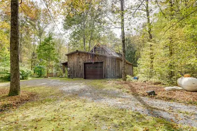 a barn in the middle of a road in the woods at Secluded Family Getaway with On-Site Creek in Hawley in Hawley