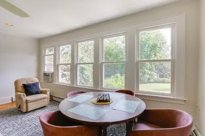 a living room with a table and chairs and windows at Walk to Hudson River Waterfront Newburgh Home in Newburgh
