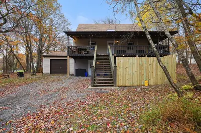 a house with a deck and a fence at Winter retreat, hot tub, game room, indoor pool, in Long Pond