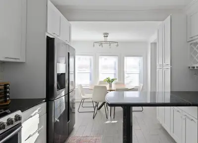 a white kitchen with a table and a dining room at 20 min to NYC, Newly Renovated, Private Driveway in Little Ferry