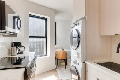 a white kitchen with a microwave and a window at Blueground Alphabet City view nr Tompkins Square Park NYC-1978 in New York