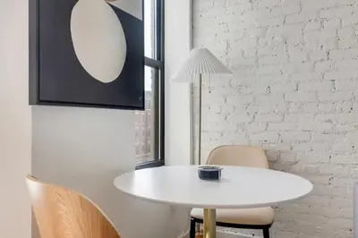 a white table and chairs in a room with a white brick wall at Blueground Alphabet City view nr Tompkins Square Park NYC-1978 in New York