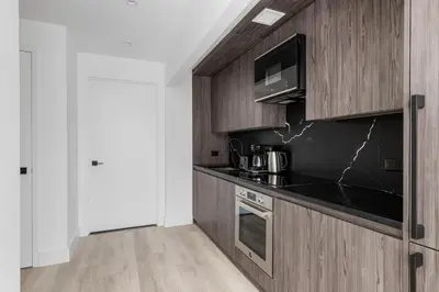 a kitchen with wooden cabinets and a black counter top at Blueground Alphabet City rooftop nr Tompkins Square Park NYC-2081 in New York