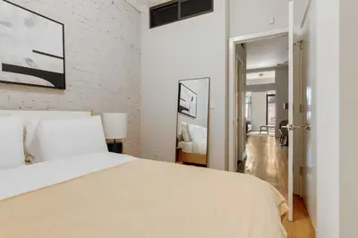 a bedroom with a white bed and a brick wall at Blueground Hells Kitchen terrace nr Times Square NYC-2063 in New York