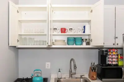 a kitchen with white cabinets and a sink at Downtown Studio Very Cozy in Albany