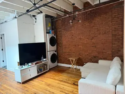 a living room with a white couch and a brick wall at ROOM IN WILLIAMBURG IN A 2BEDROOMS APt in Brooklyn
