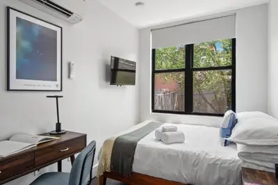 a bedroom with a bed and a desk and a window at 1 BEDROOM WITH SLEEPING IN LIVING ROOM Williamburg in Brooklyn