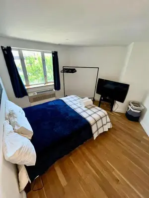 a bedroom with a blue bed and a television at 1 BEDROOM WITH SLEEPING IN LIVING ROOM Williamburg in Brooklyn