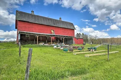 a red barn in a field with a fence at Triple Suites Close to Skiing in Pleasant Mount