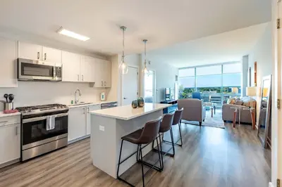 a kitchen with white cabinets and a kitchen island with bar chairs at Luxury Apartment in Stamford - Gym & Pool Access in Stamford