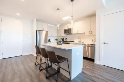 a kitchen with white cabinets and a kitchen island with bar stools at Luxury Apartment in Stamford - Gym & Pool Access in Stamford