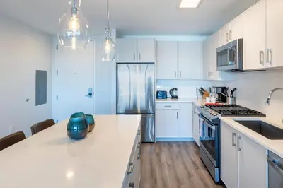 a kitchen with white cabinets and a stainless steel refrigerator at Luxury Apartment in Stamford - Gym & Pool Access in Stamford