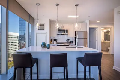 a kitchen with a large white island with black chairs at Chic Stamford Apartment - Walk to Train & Entertainment in Stamford