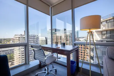 a desk with a lamp and a chair in a room with windows at Chic Stamford Apartment - Walk to Train & Entertainment in Stamford
