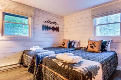 two beds in a room with wooden walls and windows at Hike, Ski and Relax Renovated Retreat in Wilmington in Wilmington