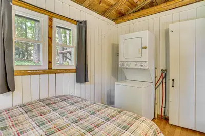 a bedroom with a bed and a refrigerator and window at Boat, Hike and Fish Rustic Greenwood Retreat in Greentown