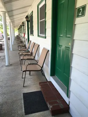 a row of chairs sitting next to a building with a green door at McGregor Inn Motel in Saratoga Springs