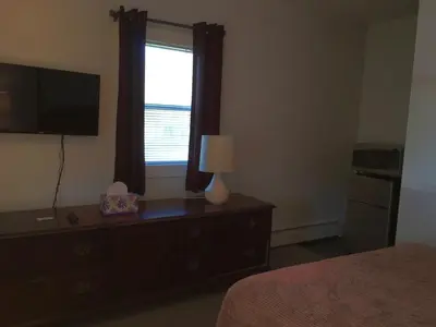 a bedroom with a dresser with a television and a window at McGregor Inn Motel in Saratoga Springs