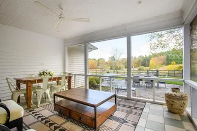 a screened in porch with a table and a dining room at Elegant 7BR Estate with Pool & Hot Tub in Berkshires in North Egremont