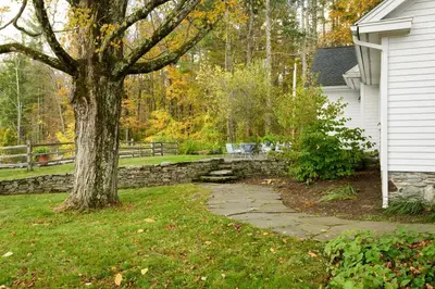 a tree in a yard next to a house at Elegant 7BR Estate with Pool & Hot Tub in Berkshires in North Egremont