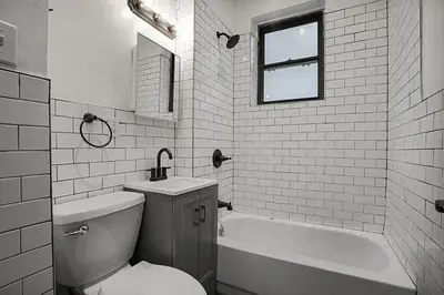 a bathroom with a toilet and a tub and a sink at The Marquee House in New York