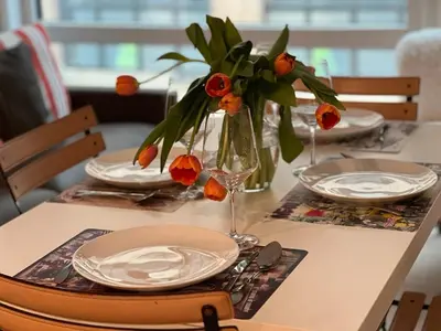 a table with plates and a vase with flowers on it at Brooklyn - Dumbo - 2-bedroom, 2-bath apartment in Brooklyn